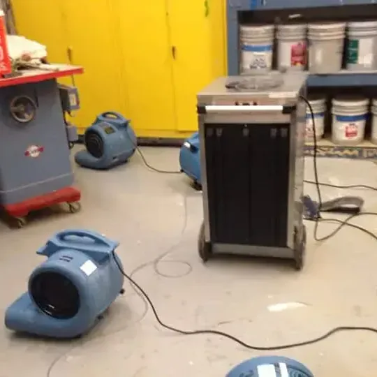Air movers and a dehumidifier set up on a garage workshop floor