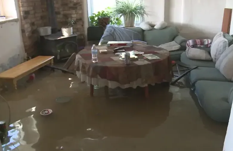Brown floodwater standing in a living room around a table and sofas